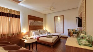 A hotel room with a bed, a desk, a chair, a TV, and a decorative wall panel. - Hotel Prince Gardens (Coimbatore)