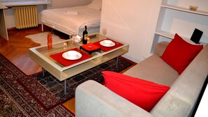 A modern hotel room with a bed, a dining table with red placemats, a glass coffee table, and a red sofa. - West Apartments Mazowiecka 7 (Warsaw)