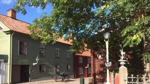 Une rue pavée bordée de bâtiments historiques, un lampadaire d’époque et une enseigne de café.