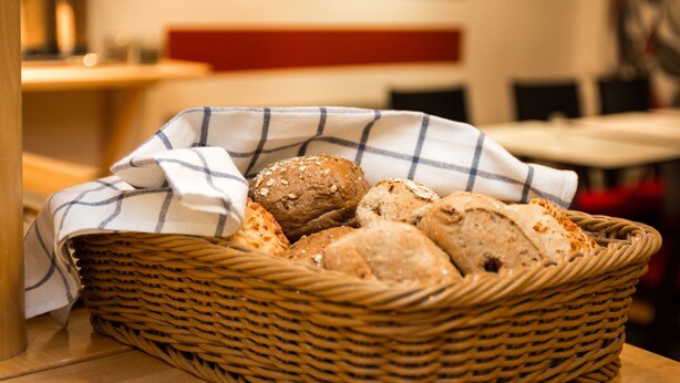 Un panier en osier rempli de différents types de pain, posé sur une table dans un restaurant.