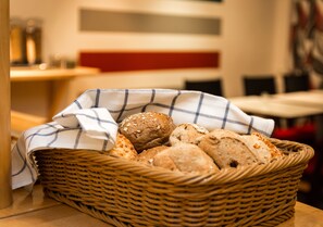 Un cesto di vimini pieno di diversi tipi di pane, posizionato su un tavolo in un ristorante.