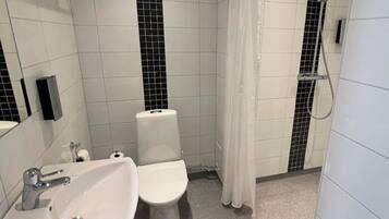 A modern bathroom with a white sink, toilet, and shower area.