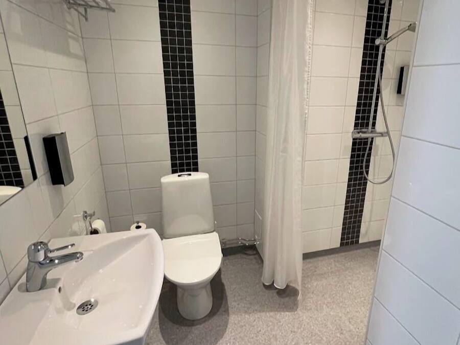 A modern bathroom with a white sink, toilet, and shower area.