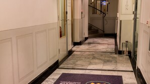 Un couloir d’hôtel avec un panneau indiquant la réception, une zone recouverte de moquette et un escalier.