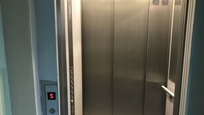 An elevator with a digital display showing the number 5, metallic walls, and a lighted ceiling. - West Apartments Hoża 36 (Warsaw)