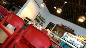 A restaurant interior with red chairs, a counter with food items, and a menu board.