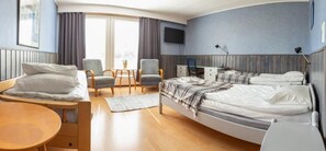 Ein Hotelzimmer mit einem Bett, zwei Sesseln, einem Schreibtisch und einem Fernseher.