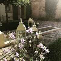 Un cortile con pavimentazione in pietra, lanterne bianche e fiori in fiore.
