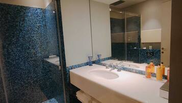 A bathroom with a glass shower enclosure, a white sink, and a large mirror.