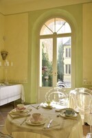 Una sala da pranzo con un tavolo imbandito per quattro persone, una finestra vista giardino e un lampadario a parete.