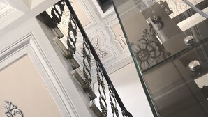 Uma escadaria com elegantes grades de metal e painéis decorativos na parede.