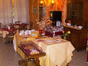 Un espace repas avec plusieurs tables dressées pour le service, proposant divers plats et un buffet.