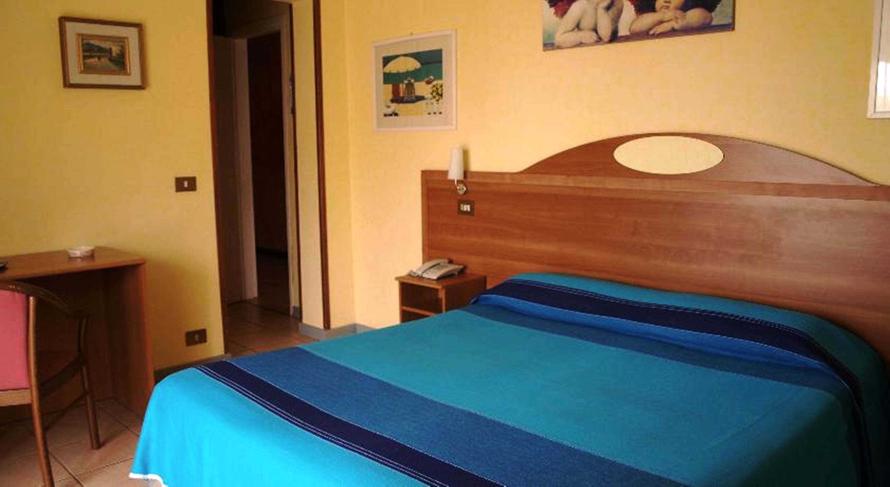 Een hotelkamer met een bed, een bureau en een nachtkastje.