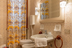 Un baño con baldosas estampadas, un inodoro, un lavabo con una toalla, un espejo y un dispensador de jabón.