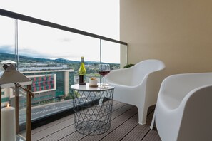 A balcony with two white chairs, a round table with a bottle of wine and a glass, and a candle. - Your Base Dublin - Sandyford (Dublin)
