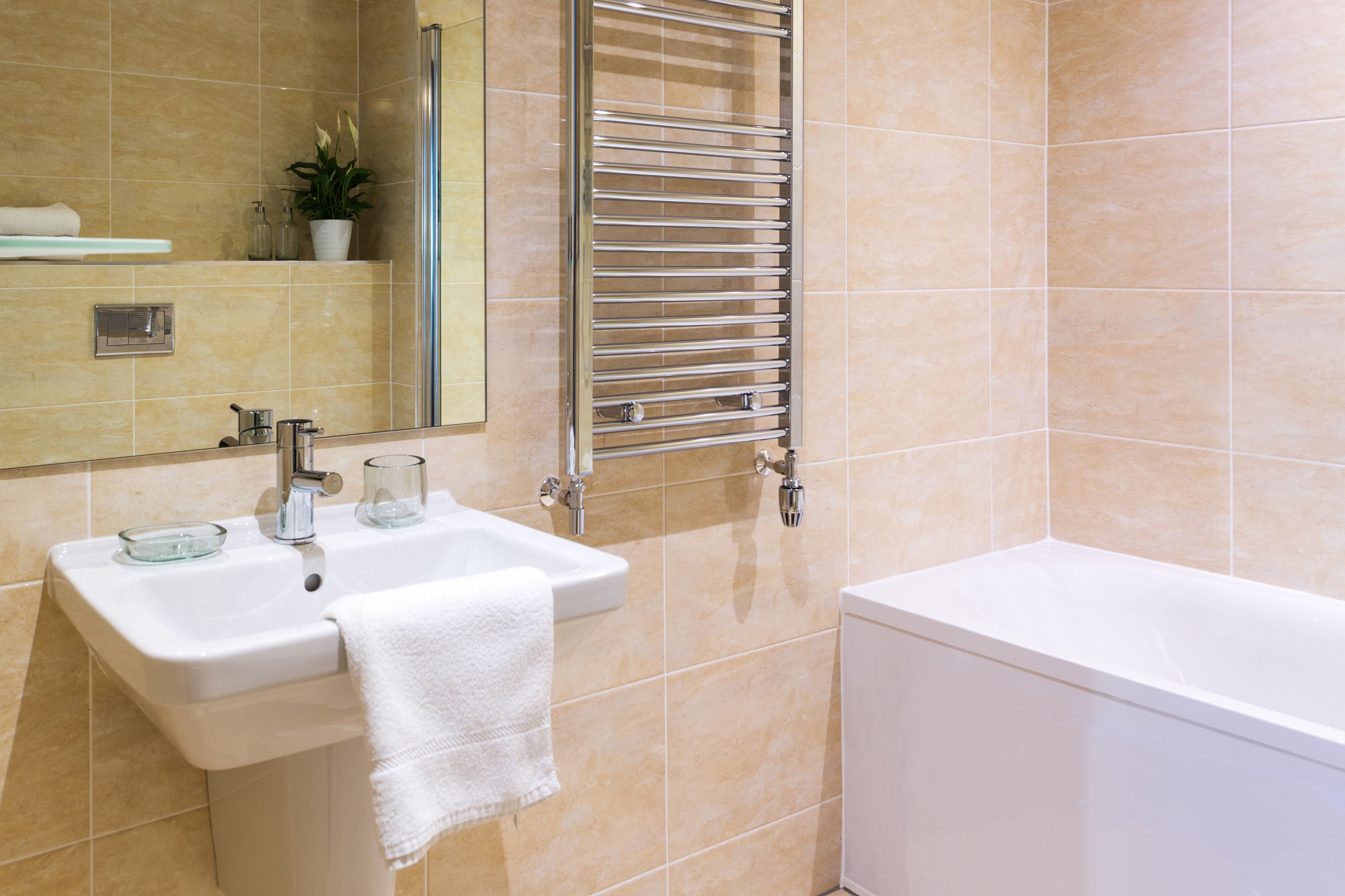 Un baño con lavamanos, espejo, toallero y bañera.