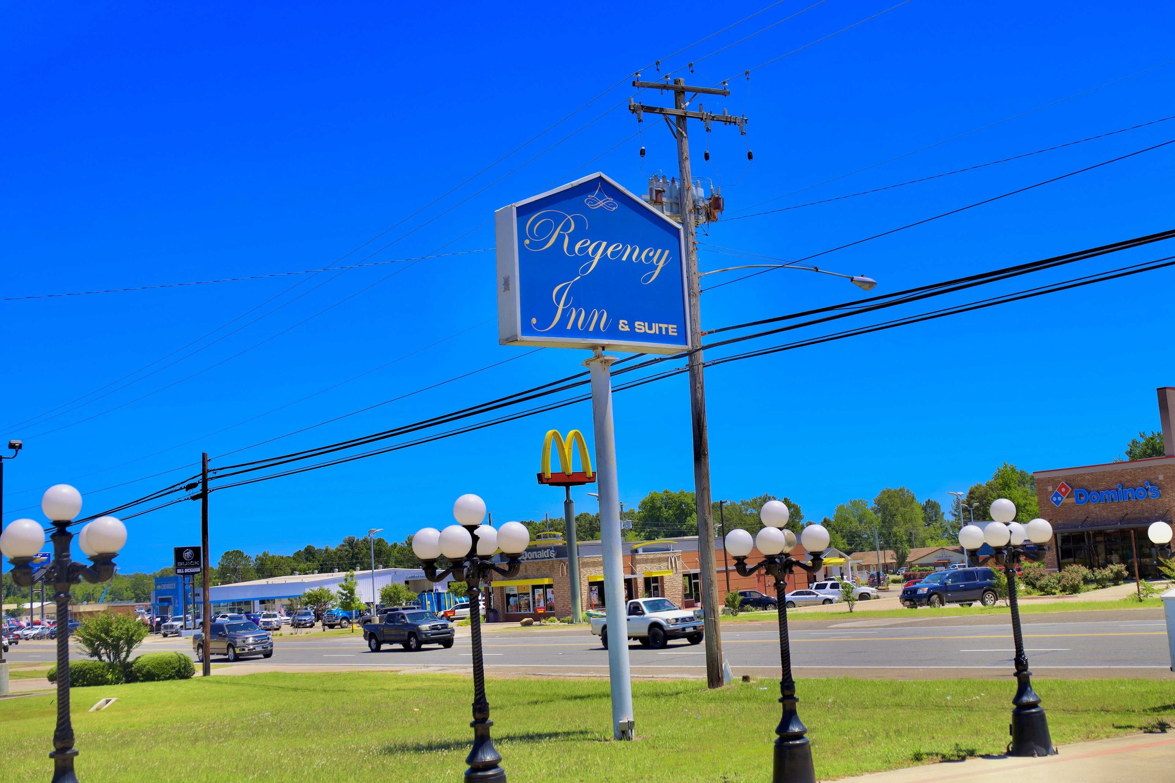 A blue sign for Regency Inn & Suites with a McDonald's and Domino's in the background.