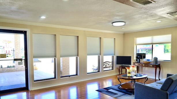 A spacious living room with a large sofa, a coffee table, and a television. - Regency Inn & Suites (Gladewater)