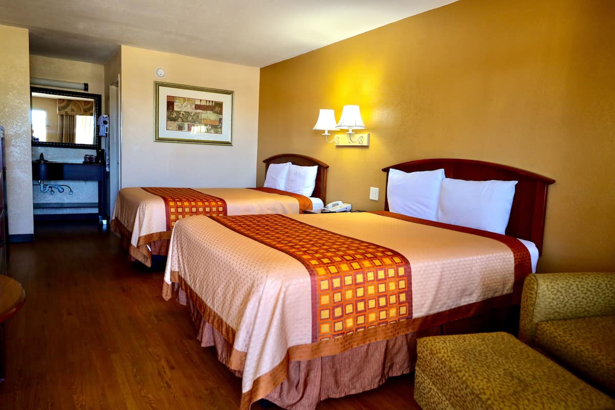A hotel room with two beds, a bathroom, and a sitting area.