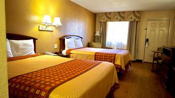 Ein Hotelzimmer mit zwei Betten, einem Schreibtisch, einem Stuhl und einer Tür.