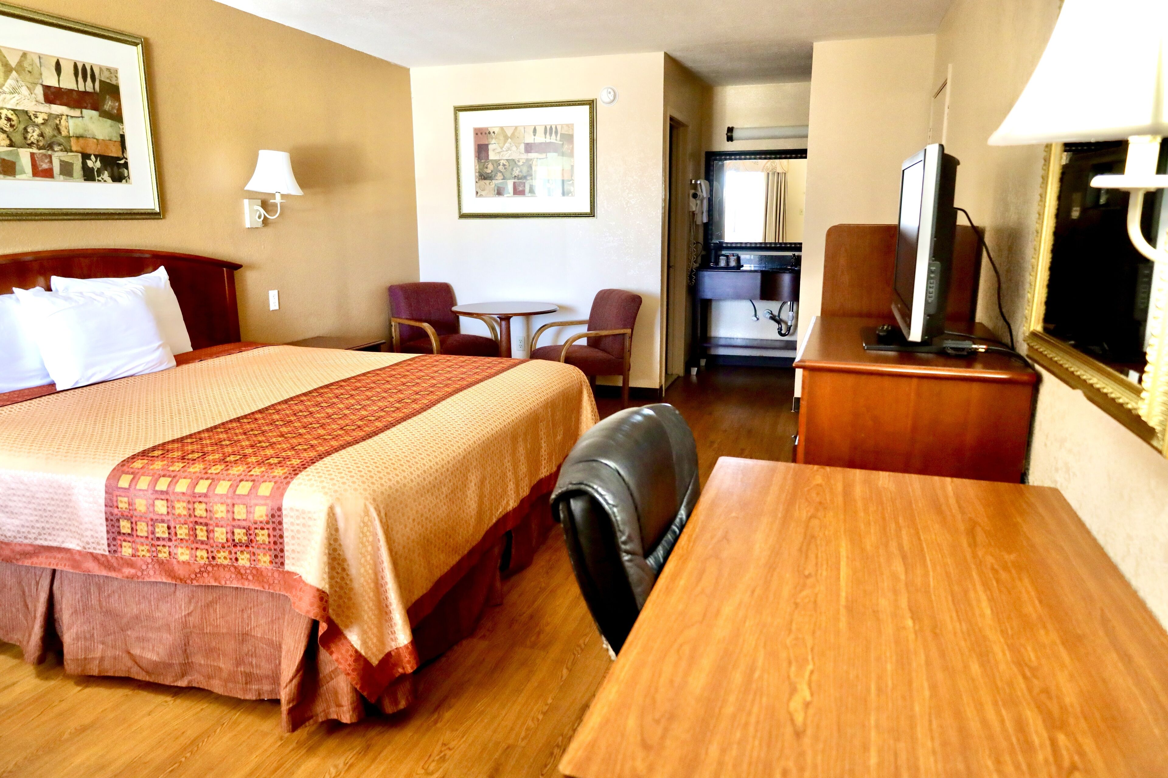 Une chambre d’hôtel équipée d’un lit, d’un bureau, d’une chaise, d’une télévision et d’une petite table.