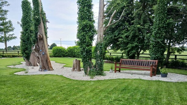 A park with a wooden bench, trees, and a gravel path. - Delphi Lodge (Ashbourne)