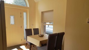 A dining area with a table and chairs, a door, and a window. - Delphi Lodge (Ashbourne)