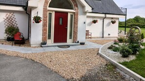 A house with a red door, a brick archway, and a gravel driveway. - Delphi Lodge (Ashbourne)