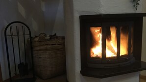 Una chimenea con llamas visibles, una cesta de mimbre y una reja metálica.
