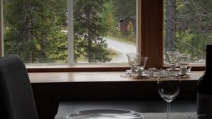 Mesa lista para comer con vista a un bosque a través de una ventana.