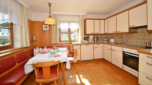 Una cocina compacta con armarios de madera, una mesa de comedor preparada para cuatro personas y un horno empotrado.