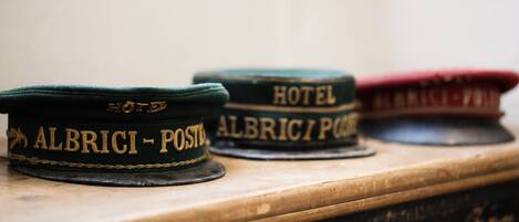 Three hats labeled "ALBRICI - POSTE," "ALBRICI - POSTE," and "HOTEL" on a wooden surface.