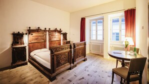 Un dormitorio con una cama de madera, una mesita de noche, un aparador y una ventana con cortinas.