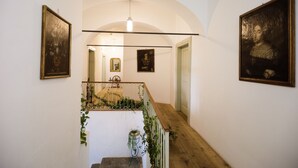 Una escalera con barandilla de madera, paredes blancas y cuadros enmarcados.