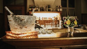 Zona de bar con mostrador de mosaicos, una botella de cerveza Pilsner y un jarrón con flores.