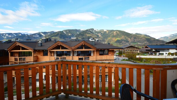 Un edificio de estilo chalé de madera con varios balcones, con montañas al fondo.