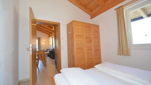Un dormitorio con un armario de madera, una cama y una ventana con cortinas.