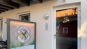 Entrada de un edificio con un letrero que indica un restaurante llamado "ZUCCHINIA" a 10 metros.