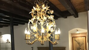 A bedroom with a large bed, a chandelier, a wooden headboard, a bedside table with a lamp, and a chair. - Casa al Teatro (Verona)