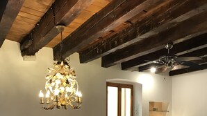 A dining area with a chandelier, wooden chairs, a table, and a view of a kitchen through an open door. - Casa al Teatro (Verona)