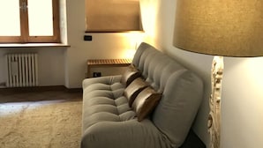 A living room with a grey sofa, a lamp, a radiator, and a window. - Casa al Teatro (Verona)