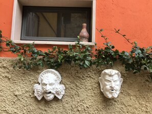 Un mur orné de deux sculptures en pierre blanche et une fenêtre avec un vase.
