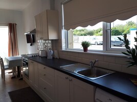 Una cocina moderna con armarios blancos, encimera negra, pileta integrada y ventana con vista a la calle.