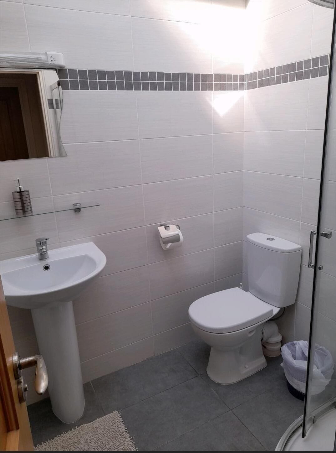 Ein Badezimmer mit Waschbecken, Toilette und Spiegel über dem Waschbecken.