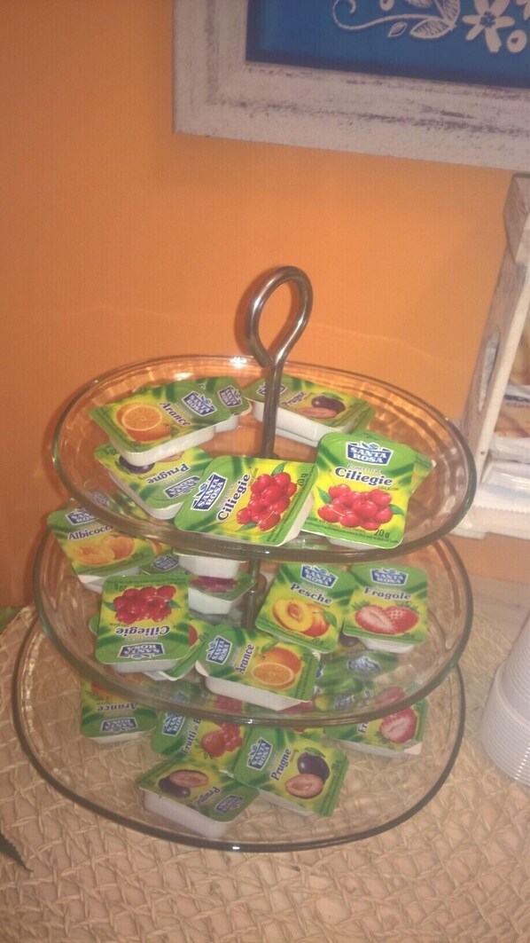 A three-tiered glass stand with various packaged food items. - B&B Anny (Naples)
