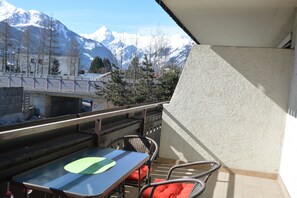 Enjoy breathtaking mountain views from this balcony with a table and two comfortable chairs.