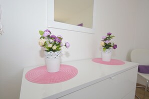 Simple, elegant room with a white dresser and two vases holding fresh flowers.