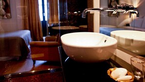 Un baño moderno con un lavamanos grande de color blanco, cabina de ducha con mampara de vidrio y un espejo.