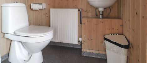 A small bathroom with a toilet, a sink, and a trash bin.