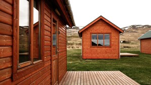 Une cabane en bois avec une terrasse, une fenêtre et une porte.